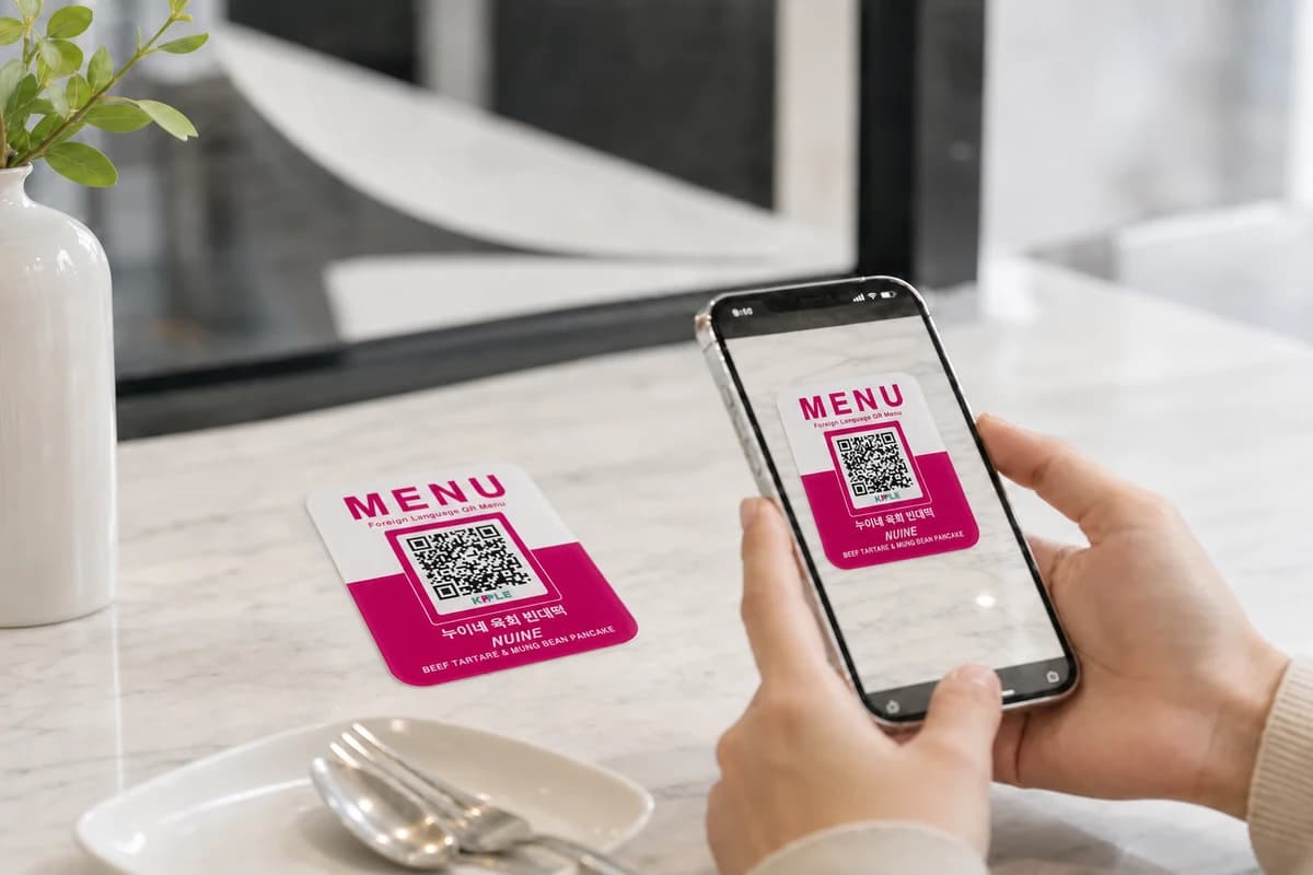테이블에 부착된 KPPLE QR 메뉴를 스마트폰으로 스캔하는 모습