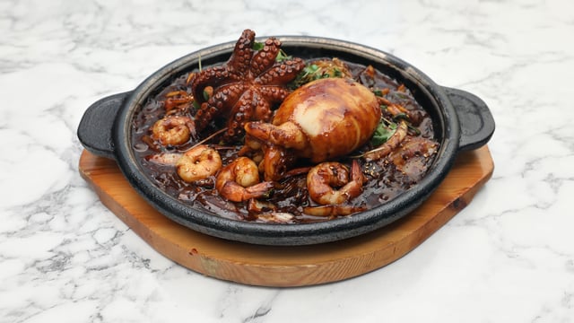 Fideos en salsa de judías negras con sepia y pulpo en plato de piedra 1